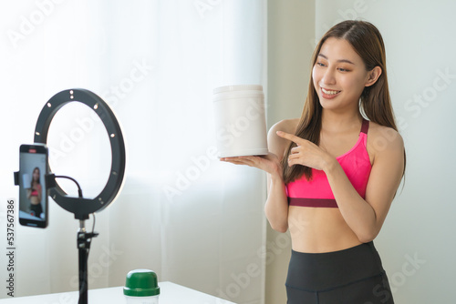 Vlogger asian young woman blogger, influencer showing product of health care, using smart mobile phone live selling food replacement, weight lose. Show goods to customer, present, streaming online.