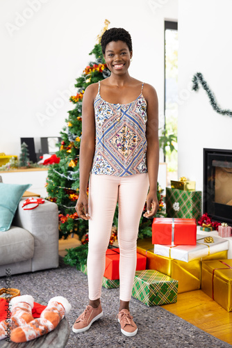 Portrait of happy african american woman with christmas tree at christmas