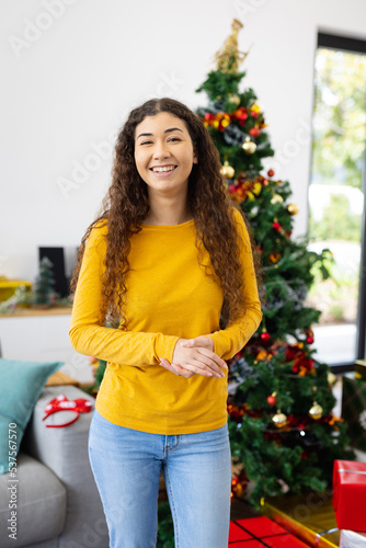 Portrait of happy biracial woman with christmas tree at christmas