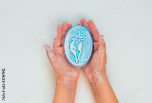 Hand washing. A child s hand holding a piece of baby soap on a white background  close-up. The concept of cleanliness and body care. View from above