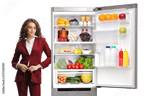 Young professional woman leaning on a fridge with food