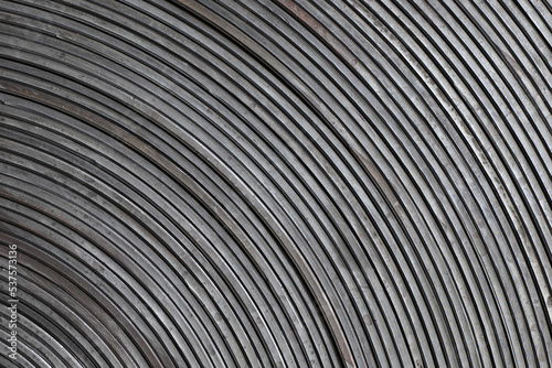 Dynamic abstract dark grey concentric bands, stripes. Artistic minimal industry photo of a rolled up conveyor belt surface.