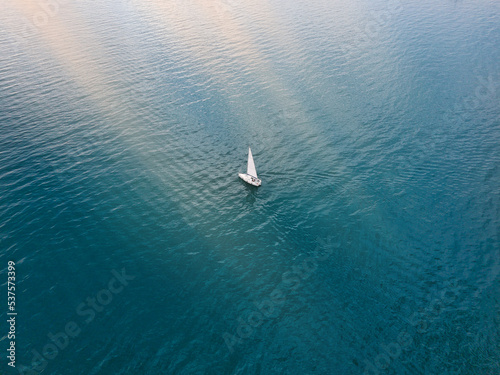 aerial view of a sailboat in the sea at sunset