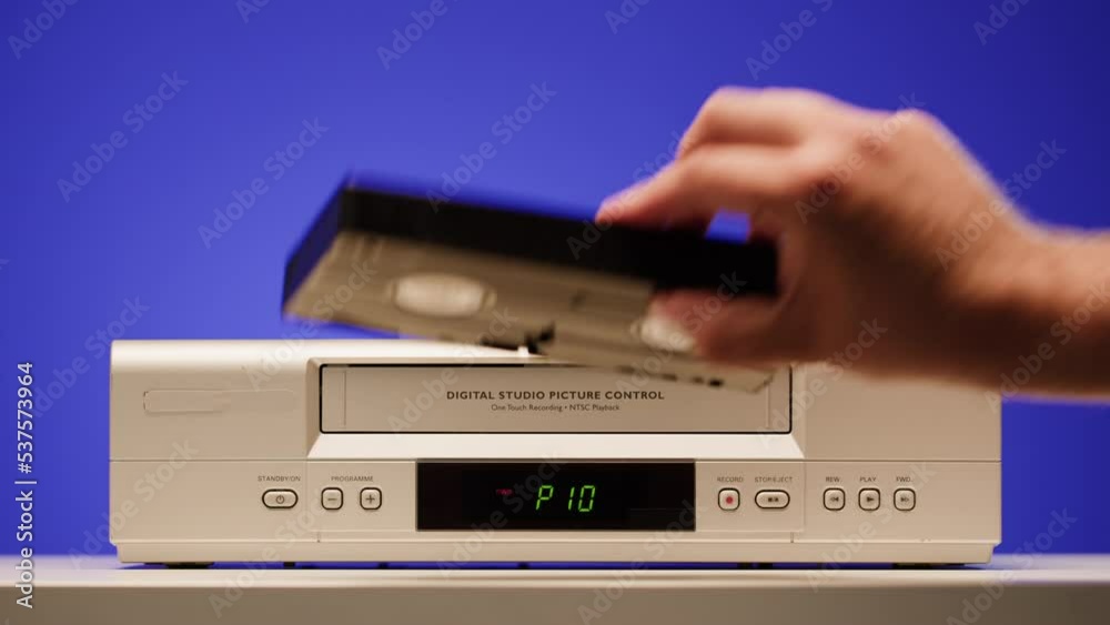Old video recorder close-up, VHS. Retro player, vintage video cassette broadcasting on blue background, audio tape. Old video recorder close-up, VHS. Retro player, vintage video cassette broadcasting on blue background, audio tape.