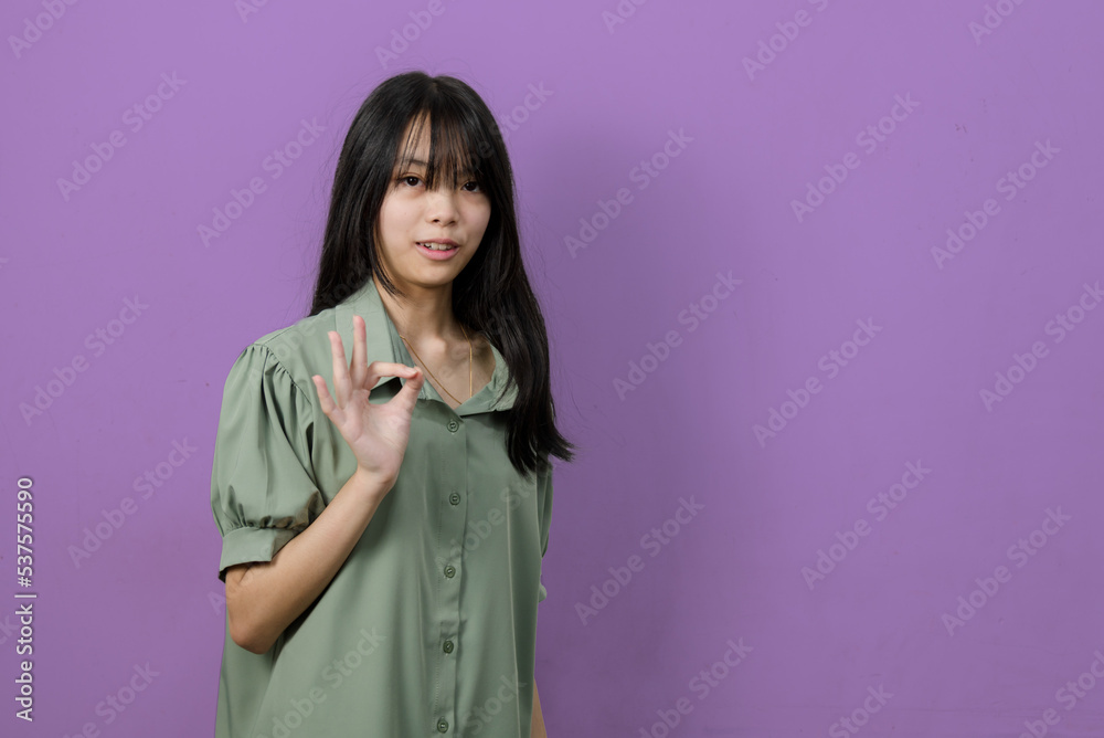 Asian teen girl portrait show hand ok on background copy space. Asian teen girl portrait show hand ok on background copy space.