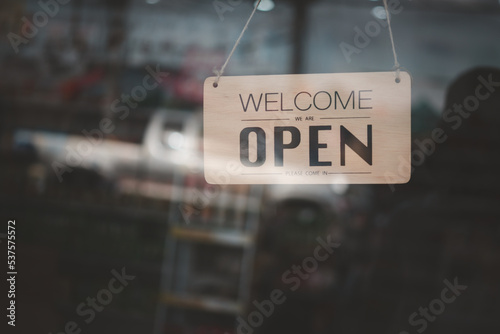 Shop opening sign at the glass door in vintage tones.