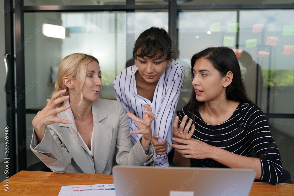 Businesswoman in group meeting discussion with other businesswomen colleagues in modern workplace office with laptop computer and documents on table. Businesswoman in group meeting discussion with other businesswomen colleagues in modern workplace office with laptop computer and documents on table.
