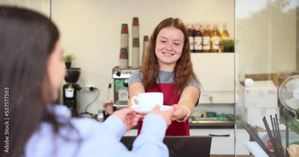 A pretty brunette lady goes to the cafe to get her coffee, the barista has a big smile on her face. A pretty brunette lady goes to the cafe to get her coffee, the barista has a big smile on her face.