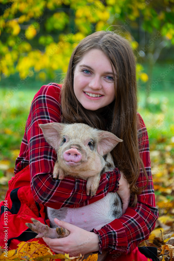 a happy farmer girl with a little piglet (kune kune) a happy farmer girl with a little piglet (kune kune)