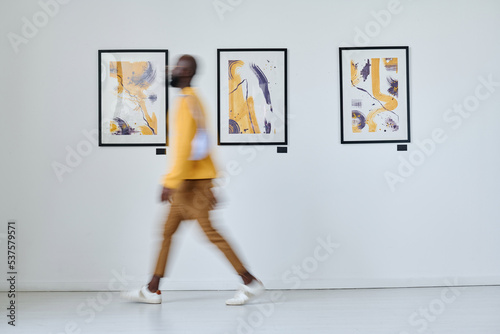 Valokuva Blurred motion of African young man walking along art gallery with pictures on t