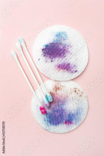 Dirty cotton pads and sticks after removing makeup. Vertical. Pink background. Dirty cosmetic pad after removing make-up. Hygiene concept.