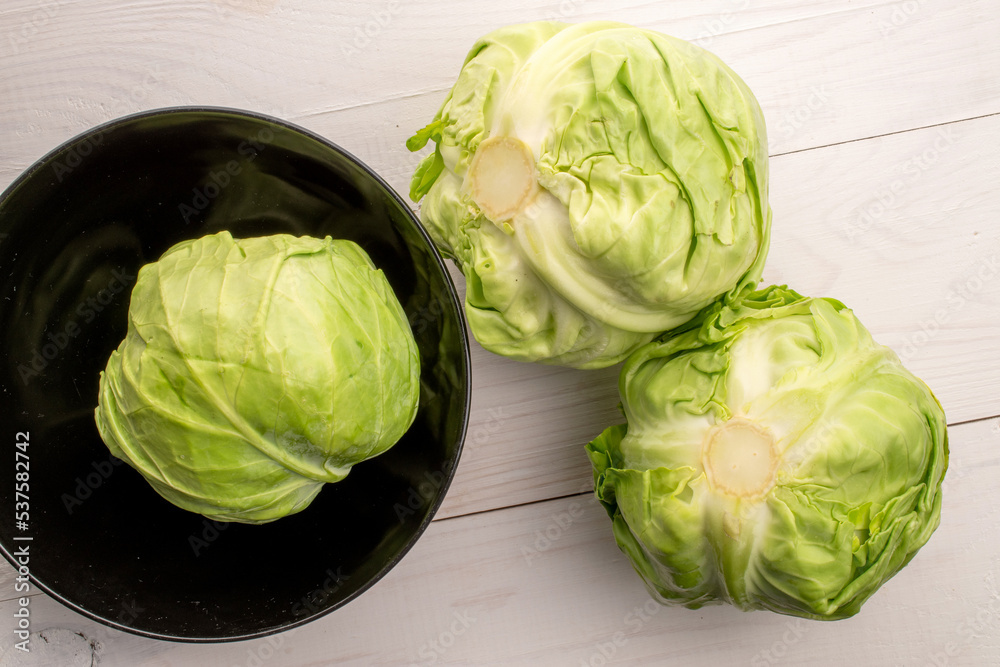 Fototapeta premium Three juicy organic cabbage on a painted wooden table, top view.
