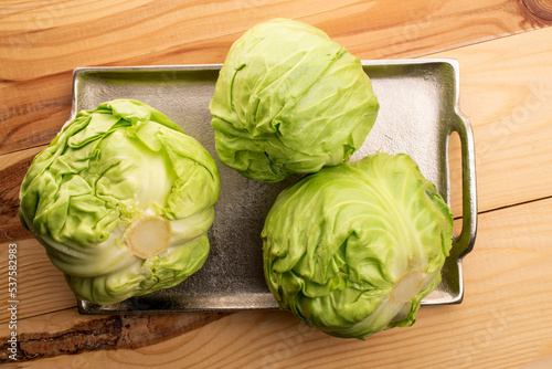 Three tasty juicy natural cabbage on a metal tray, on a  wooden table, top view.