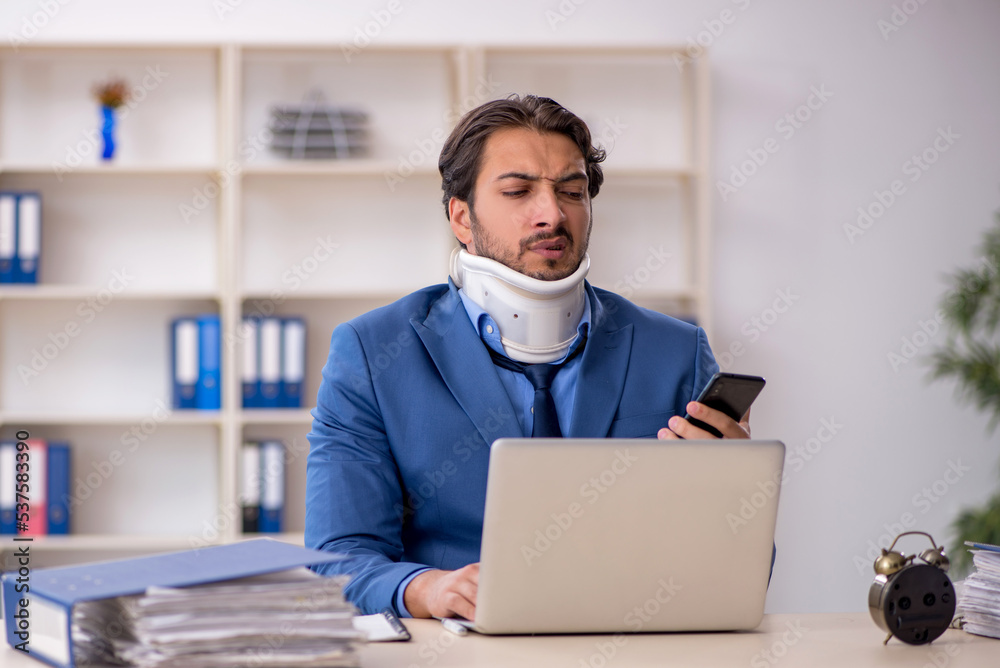 Young male employee after accident sitting at workplace