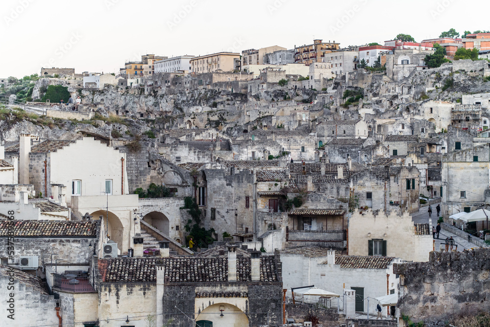 old stone houses and churches on the ravine slopes in the historic center of the old town of Matera. Narrow cobbled streets and cascading buildings with rocks and tightly built-up streets