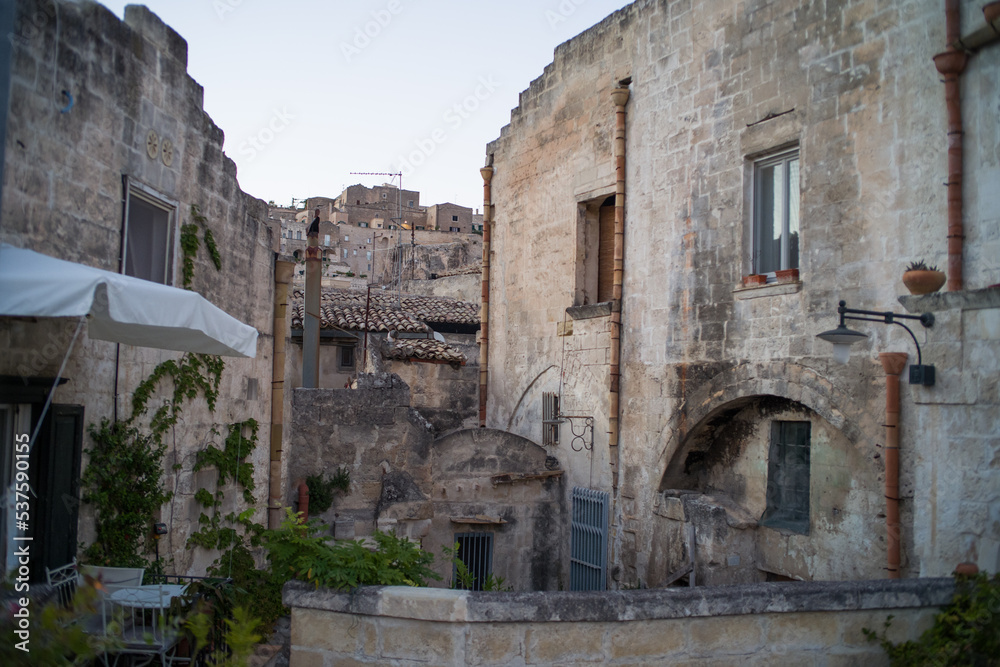 old stone houses and churches on the ravine slopes in the historic center of the old town of Matera. Narrow cobbled streets and cascading buildings with rocks and tightly built-up streets