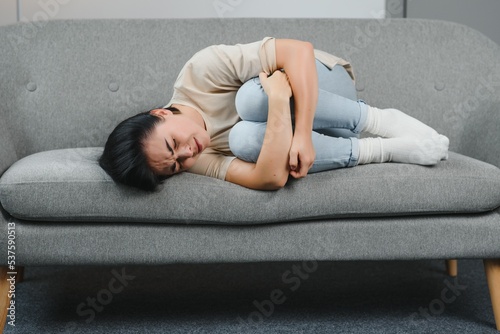 Young woman lying in the bed and suffering from gynecological problems  menstruation pain  stomach ache or abdominal pain. Menstruation period or PMS.