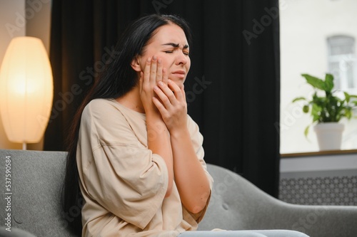 Attractive young woman suffering from toothache. Woman holding her cheek in pain.