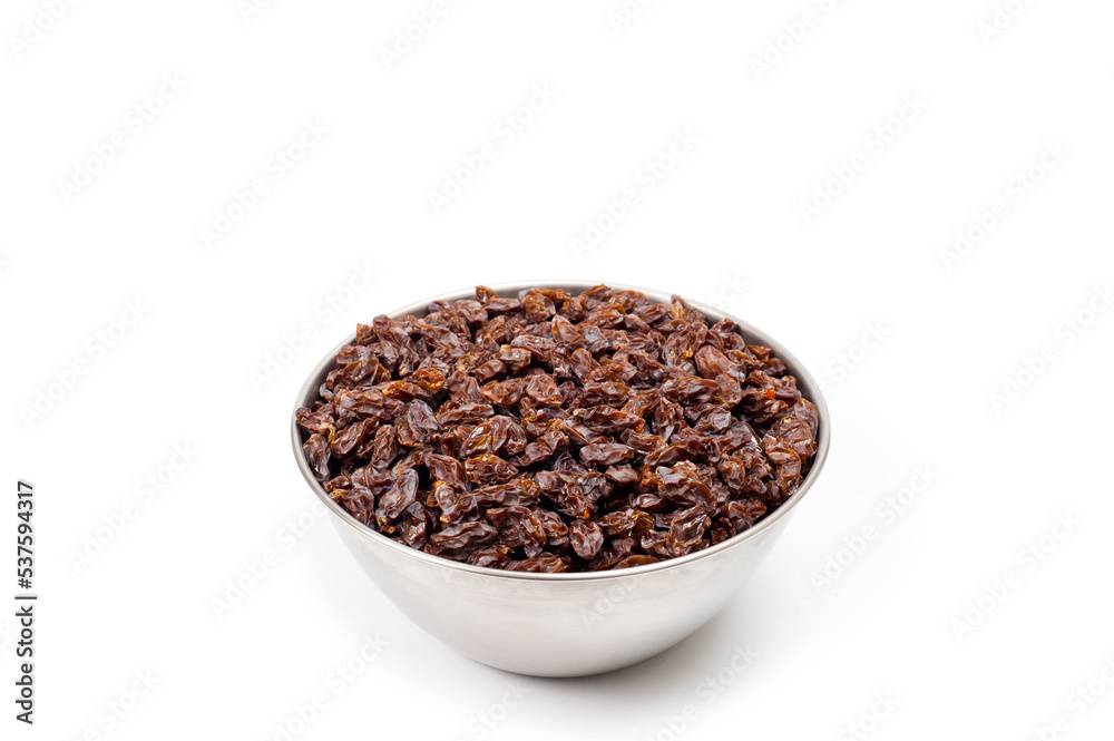 Dark-colored raisins lying in a metal container, shot on a white background. Dark-colored raisins lying in a metal container, shot on a white background.