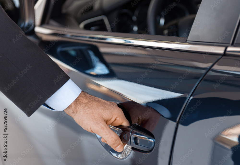 Close up of a male customer hand opening a car door at the dealership