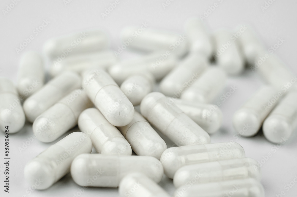 White medical capsules on a white background, selective focus White medical capsules on a white background, selective focus