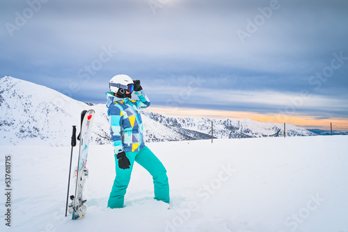 Portrait of a woman skier looking ahead on ski piste in snowy Pyrenees Mountains. Skis planted in deep snow. El Tarter, Grandvalira, Andorra
