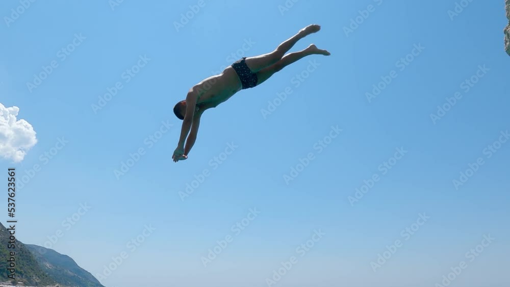 Adrenaline head jump. Young man jumping in turquoise water during summer vacation on Kathisma beach in Lefkada, Greece, slow motion Adrenaline head jump. Young man jumping in turquoise water during summer vacation on Kathisma beach in Lefkada, Greece, slow motion
