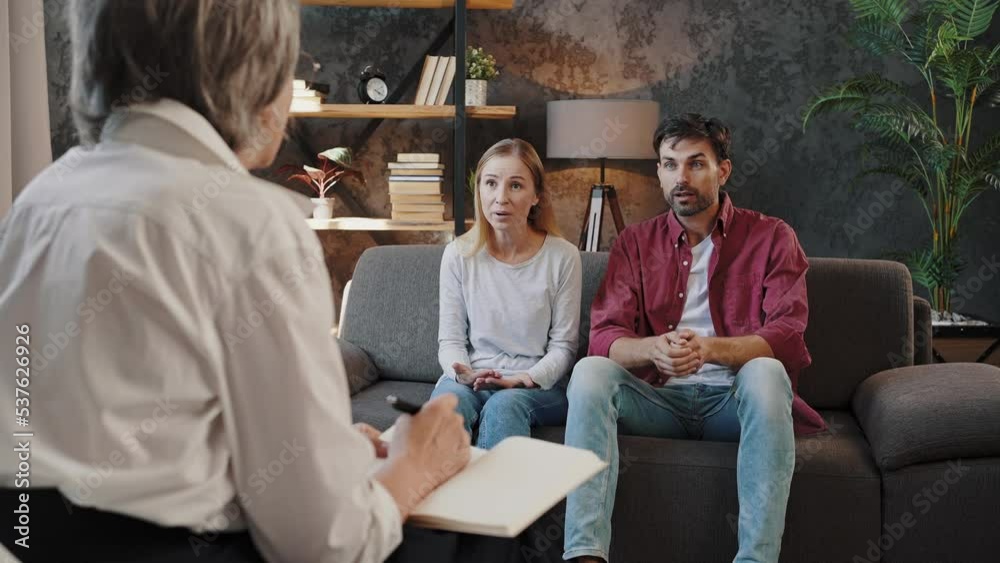 Man and woman argue sitting on couch at psychologist office