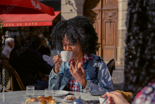 young haitian woman drinking coffee with her eyes closed in an outdoor cafe in autumn