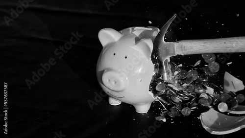 1000fps slow motion clip of a hammer smashing a piggy bank open to spill the coins it contains; financial concept