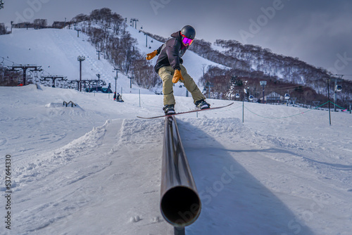 Snowboarder doing a boardslide in a rail at the snowpark photo