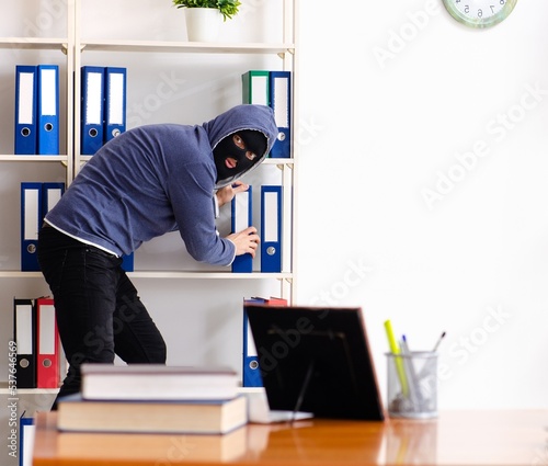 Male thief in balaclava in the office
