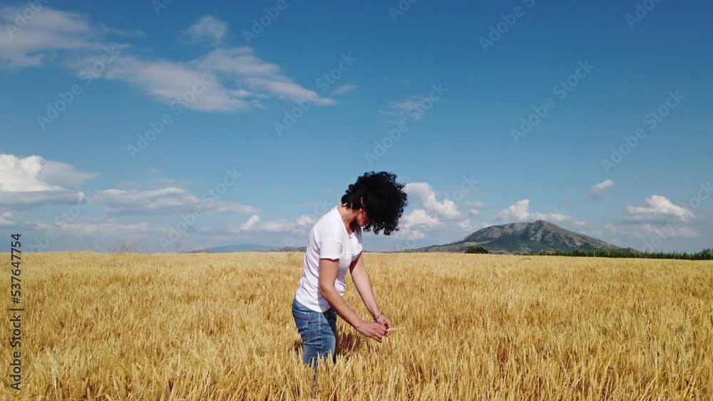 Slow motion of a happy young farmer woman holding ear of wheat and checking the quality of the wheat Slow motion of a happy young farmer woman holding ear of wheat and checking the quality of the wheat