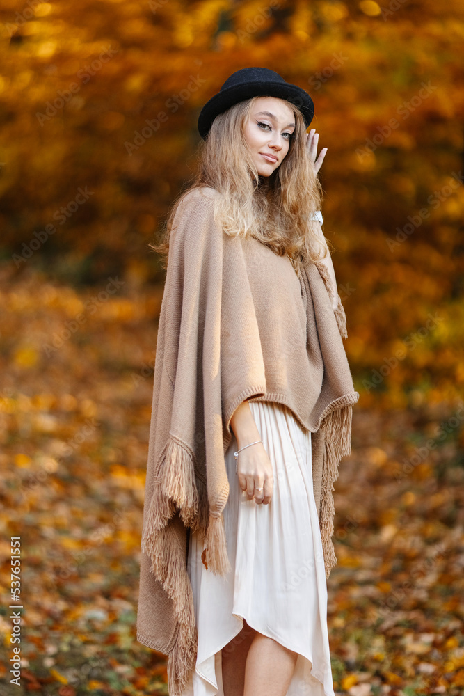 A dreamy woman in a brown poncho in the middle of an autumn yellow forest. A dreamy woman in a brown poncho in the middle of an autumn yellow forest.