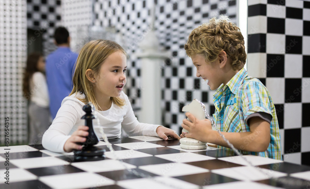 Fototapeta premium Boy adn girl solving puzzle together in quest room stylized like chessboard