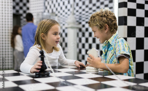 Boy adn girl solving puzzle together in quest room stylized like chessboard