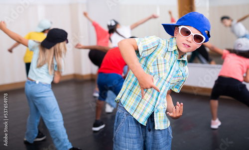 Preteen boy in cap performing hip-hop at group dance class