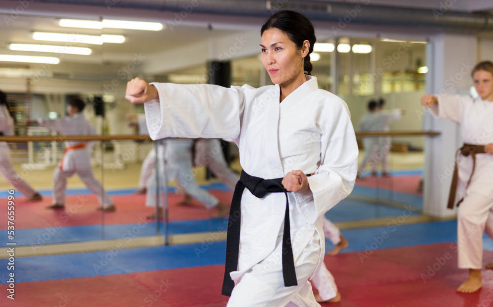 Female karate coach training boys and girls in the gym