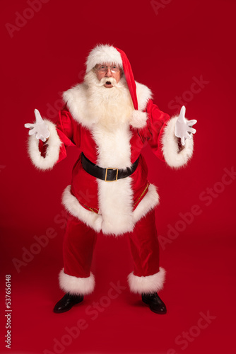 real, happy Santa Claus annoucing big xmas sale on a red studio background. Merry Christmas and Happy New Year! photo