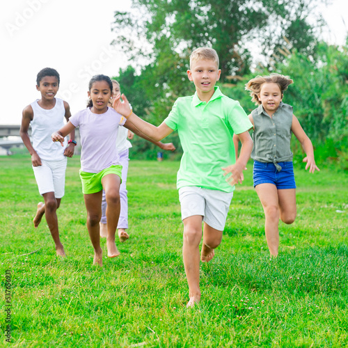 Group of five happy children who are jogging in a park on a sunny day