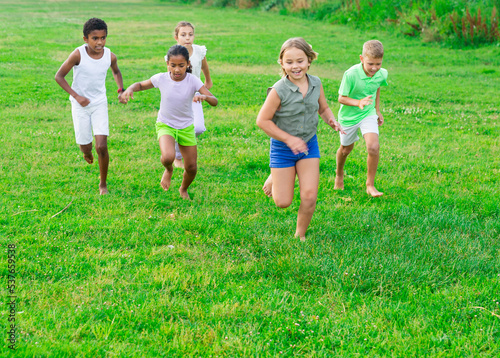 Group of laughing children having fun together outdoors running