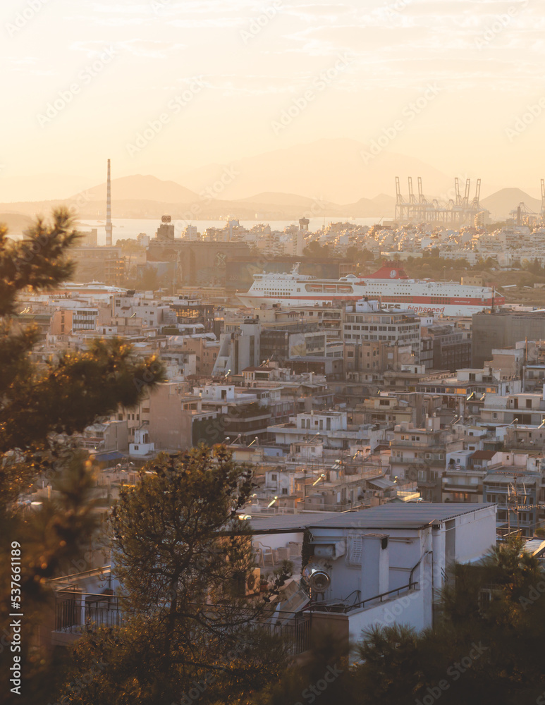 Obraz premium Piraeus city, Attica, beautiful panoramic view of Piraeus, Greece, with harbour and port, mountains and scenery beyond the city, seen from Prophet Helias Hill on Kastela Hill, sunset summer view