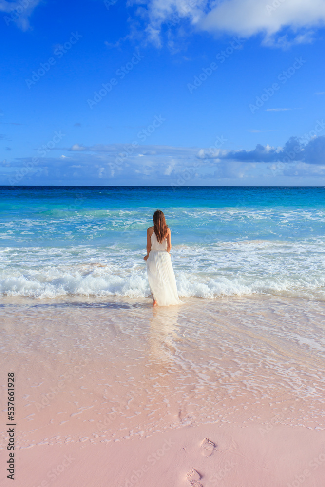Woman walking on Horseshoe Bay Beach in Bermuda, leaving footprints in the pink sand Woman walking on Horseshoe Bay Beach in Bermuda, leaving footprints in the pink sand