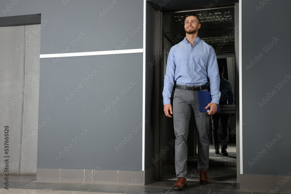 Fototapeta premium Attractive young businessman walking out modern elevator