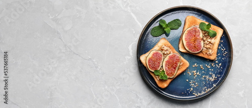 Tasty toasts with fig pieces, peanut butter and walnuts on light grey marble table, top view with space for text. Banner design