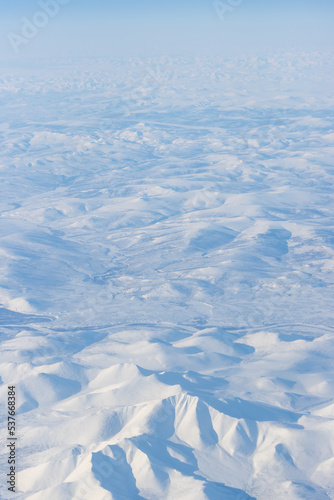 Aerial view of snow-capped mountains. Winter snowy mountain landscape. Icheghem Range, Kolyma Mountains. Koryak Okrug (Koryakia), Kamchatka Krai, Siberia, Far East of Russia. Great for backgrounds. © Andrei Stepanov