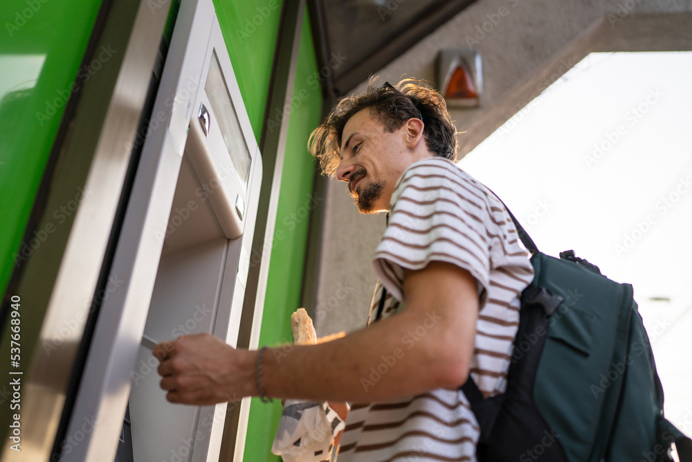 side view man use ATM machine to withdraw money with credit card side view man use ATM machine to withdraw money with credit card