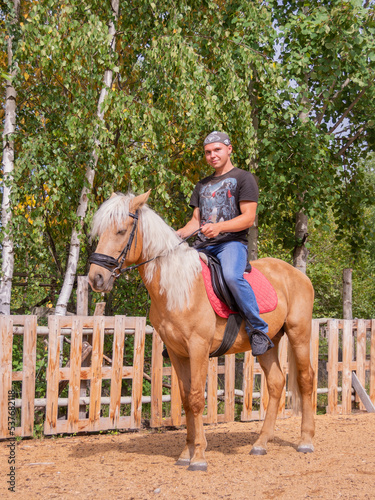 Outside on a beautiful warm day, a young man is riding a horse. © Мария Иванова