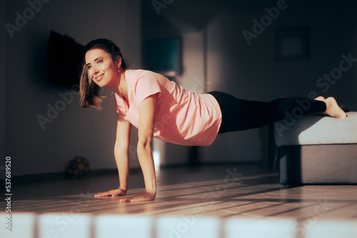Happy Woman in Plank Position Exercising at Home. Beautiful lady doing bodyweight fitness activity in the living room 