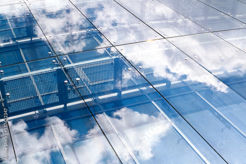 sky and clouds reflecting in the glass wall of an office building facade. abstract urban background.